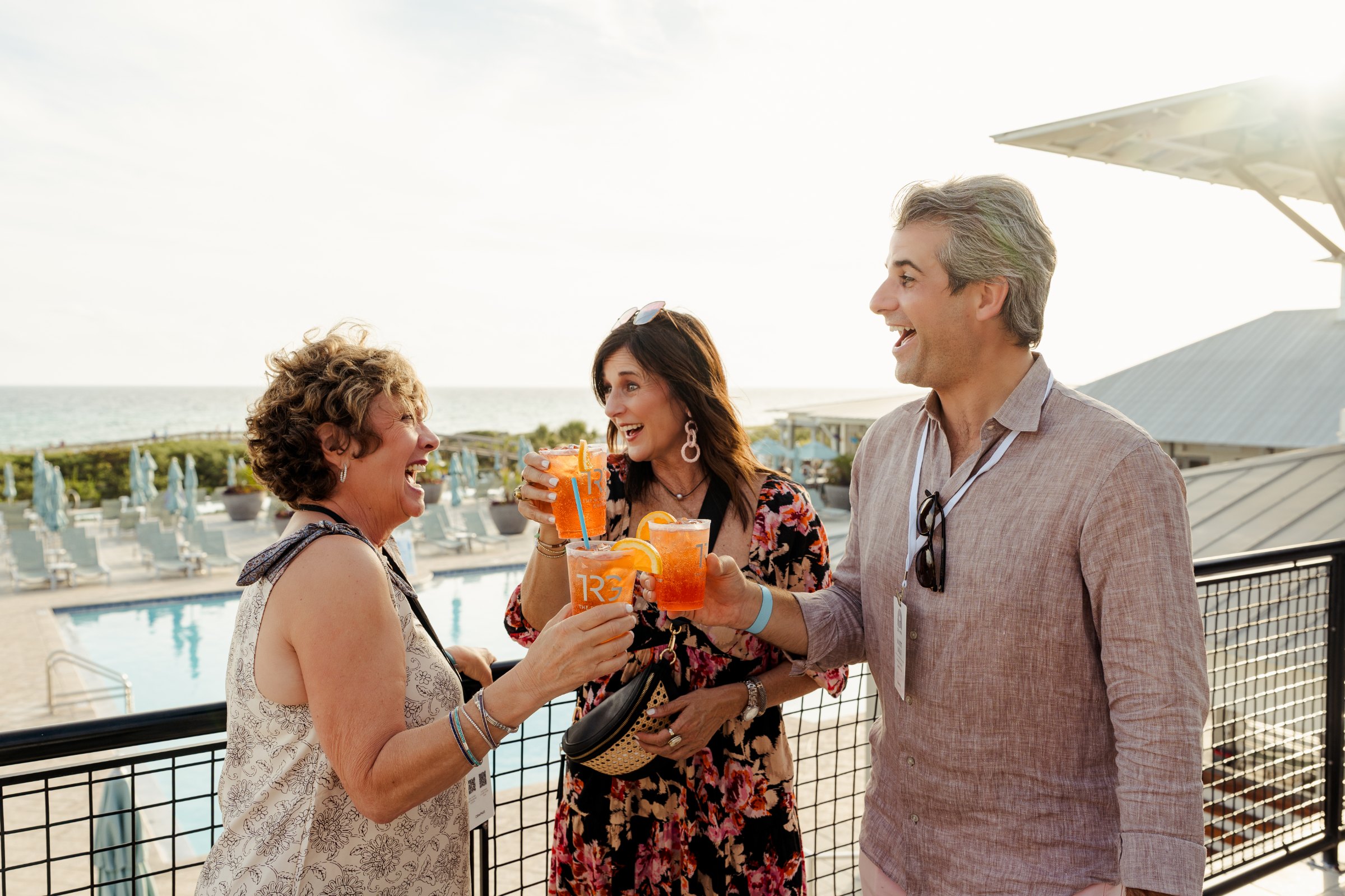 Placeholder: attendees raising their cups on a rooftop above the Gulf